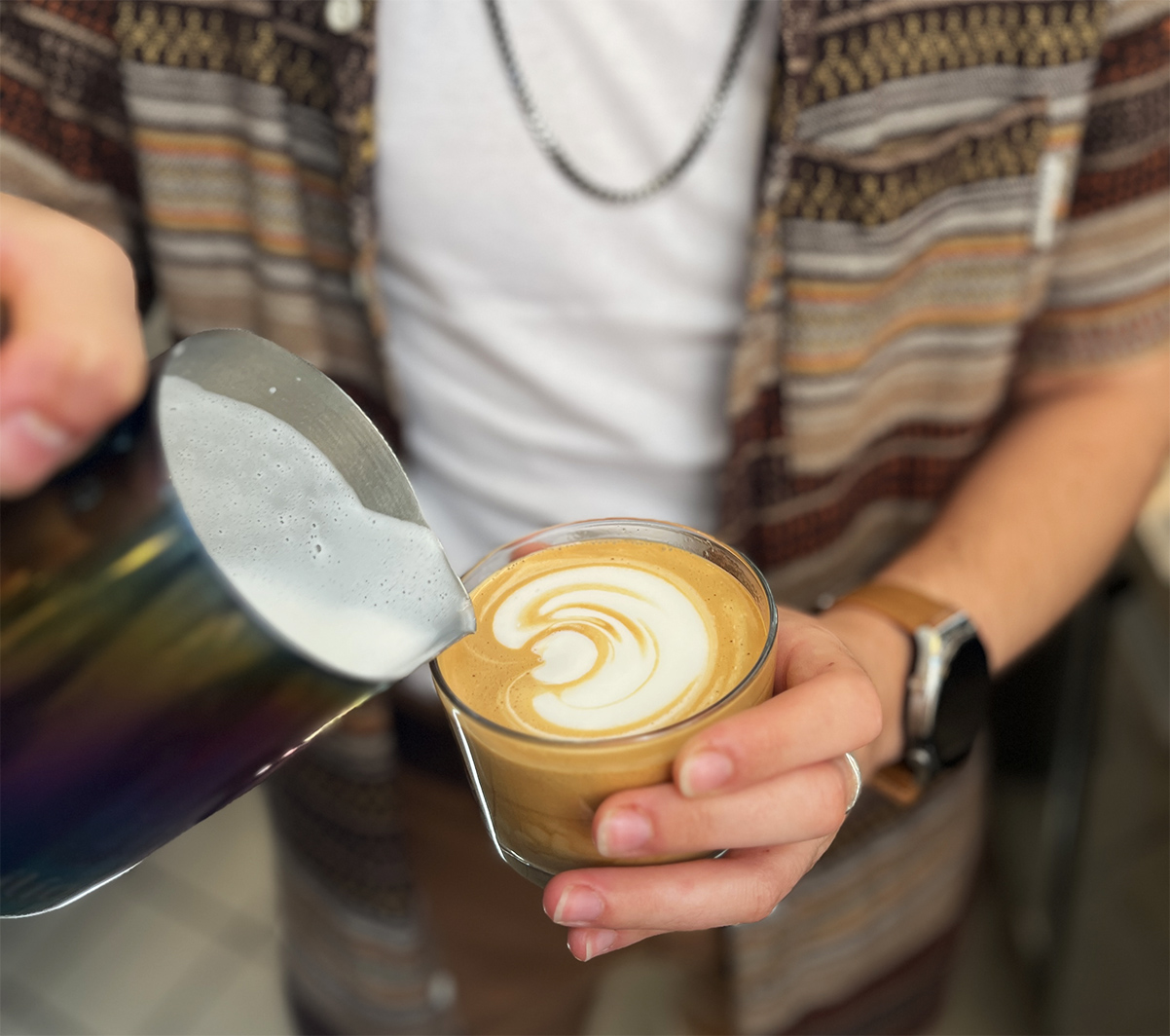 בריסטה עושה לאטה ארט על כוס קפוצ'ינו בזכוכית. צילום: דיקלה דנינו