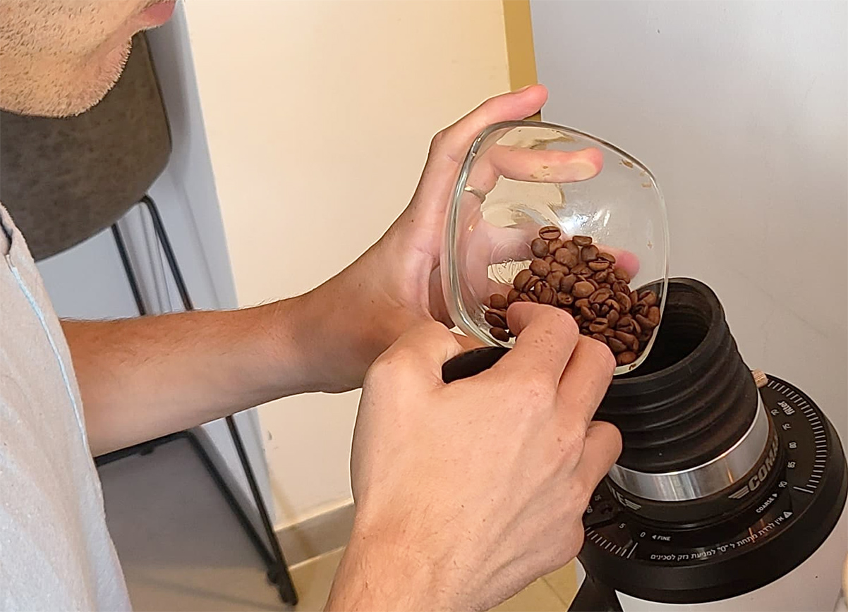 בריסטה מכניס פולי קפה למטחנה. צילום: מגזין שותים