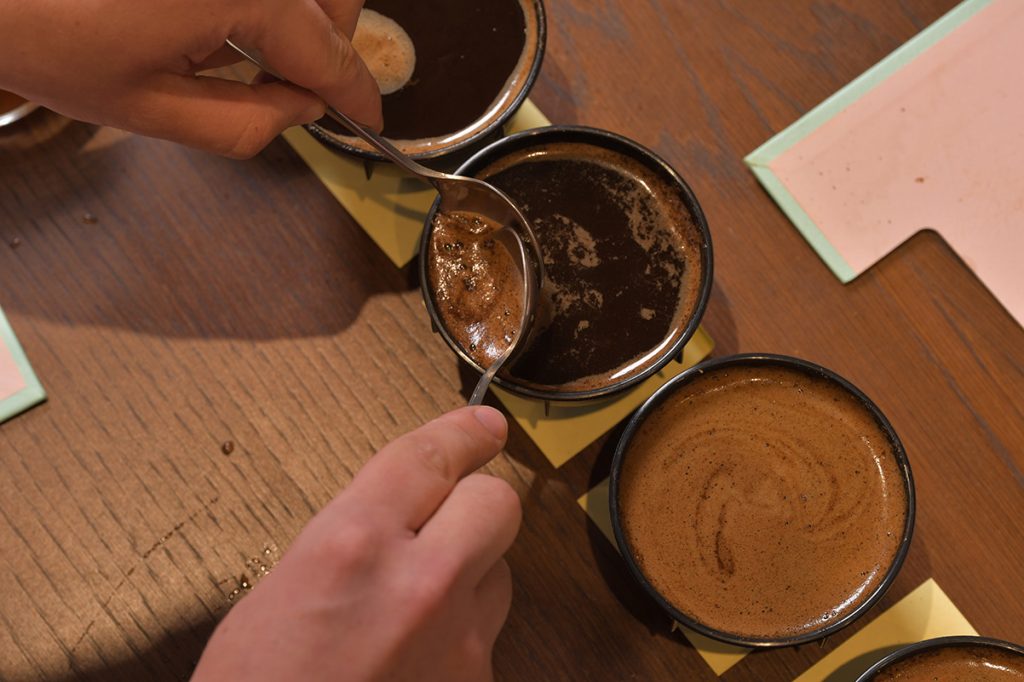 הבריסטה מסיר את הקפה הטחון הצף בעזרת שתי כפות. צילום: יעקב בלומנטל